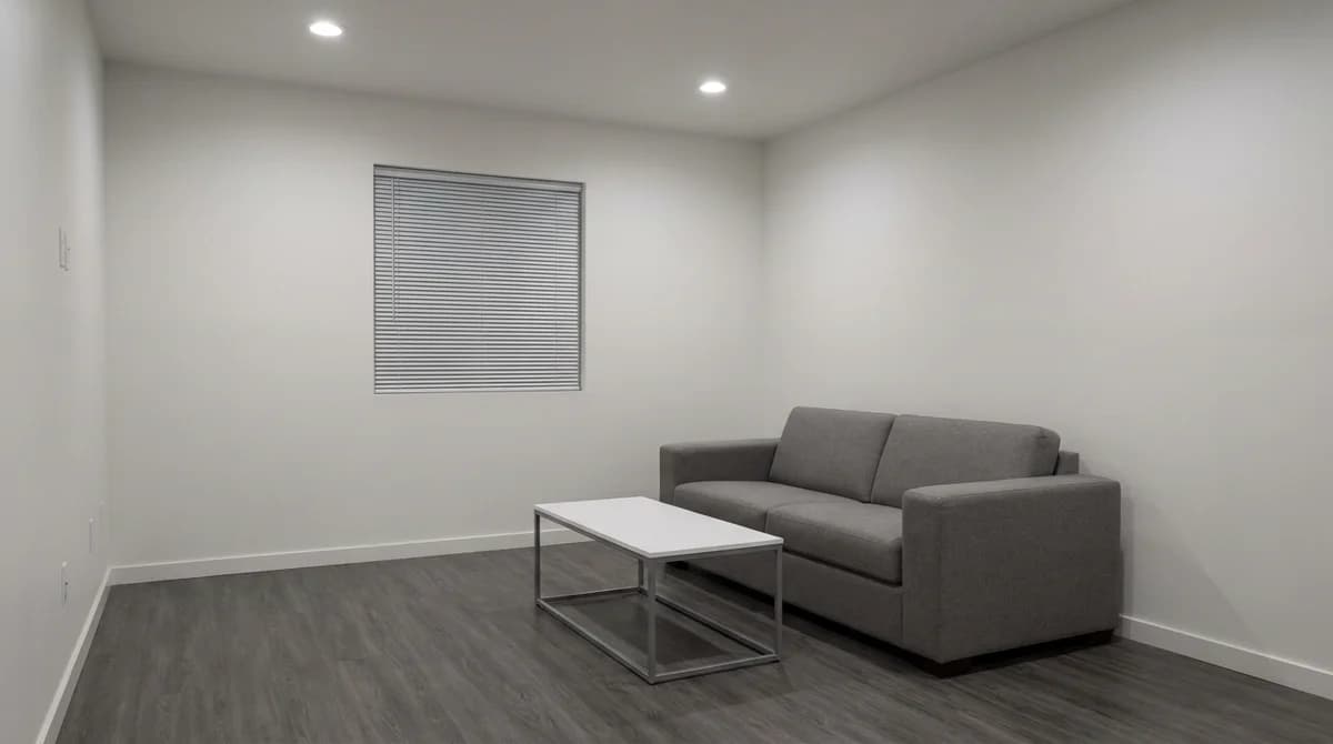 A plain, dim living room with bare walls, no plants, and closed blinds