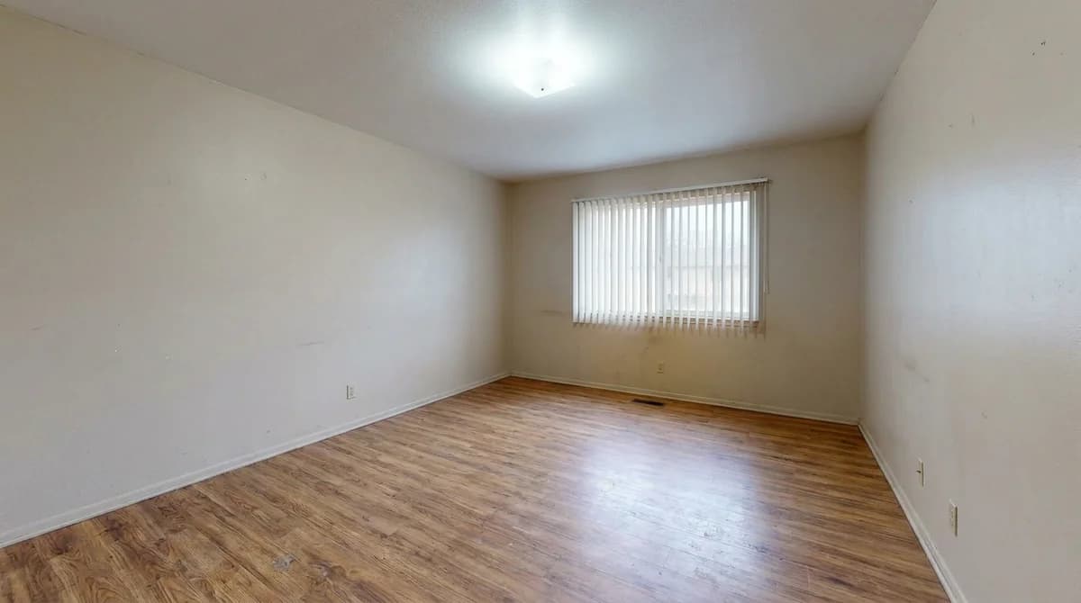 Empty unfurnished short-term rental living room with bare walls and laminate floor
