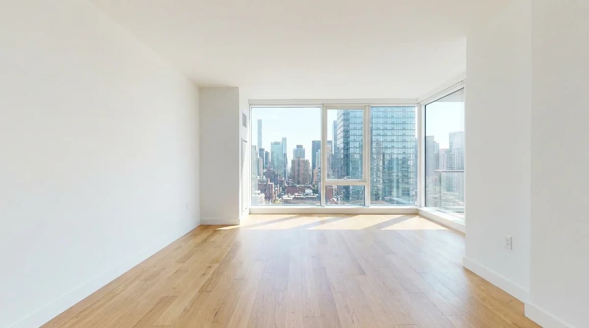 Empty unfurnished living room with bare walls and oak floors